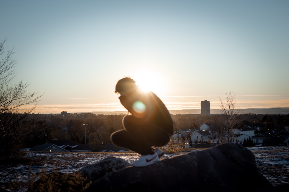 man in black jacket sitting on rock during daytime