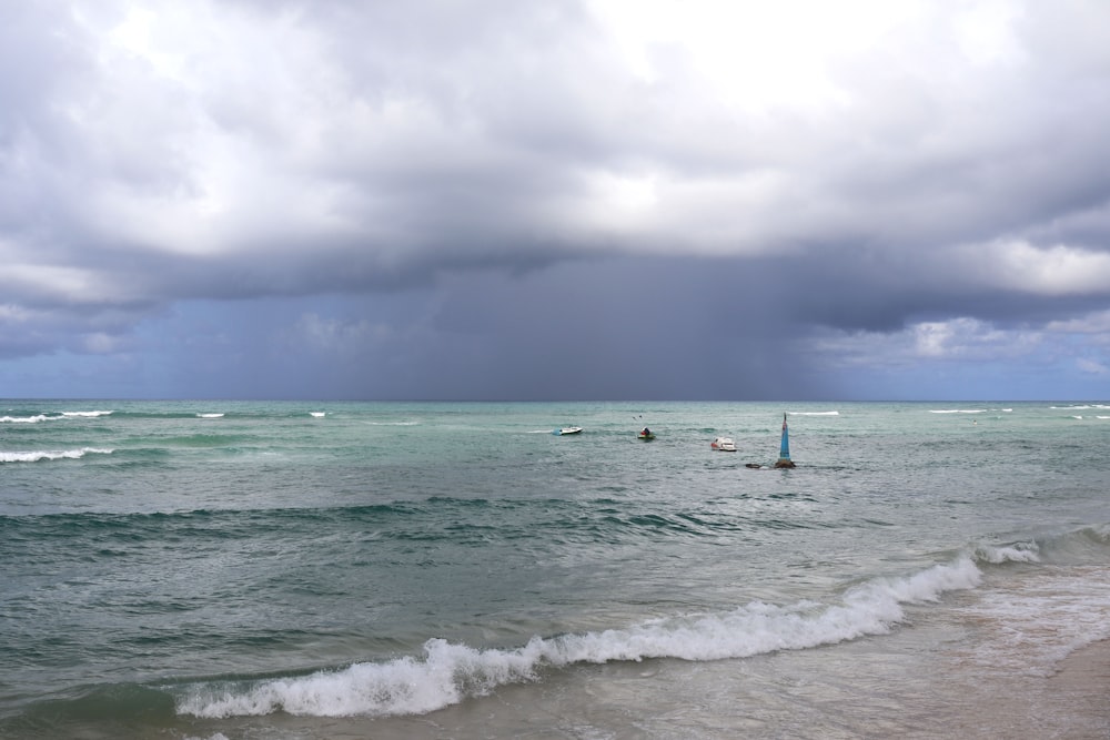 people surfing on sea waves under white clouds during daytime