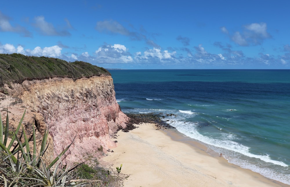 brown rocky mountain beside blue sea under blue sky during daytime