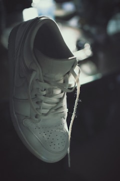 Sneaker with repaired sole and fresh white laces in elegant lighting.