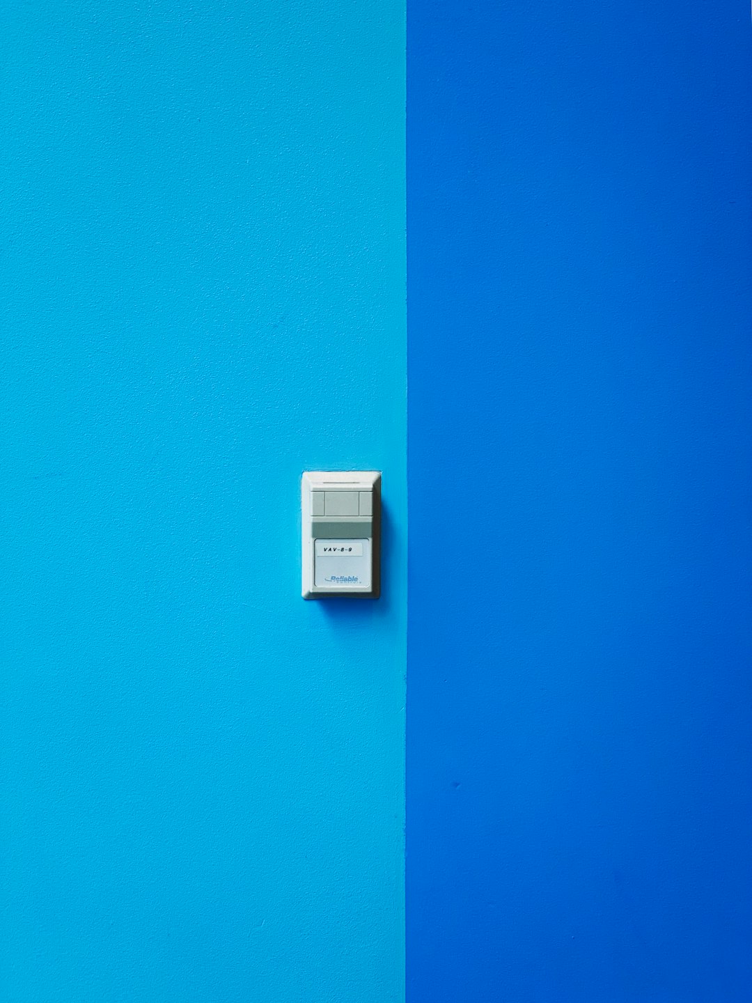 white wall mounted device on blue wall