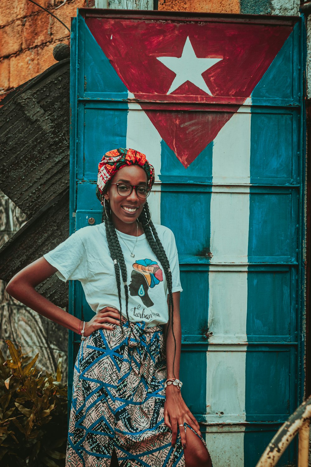 woman in white crew neck t-shirt wearing red and white floral headdress standing beside blue