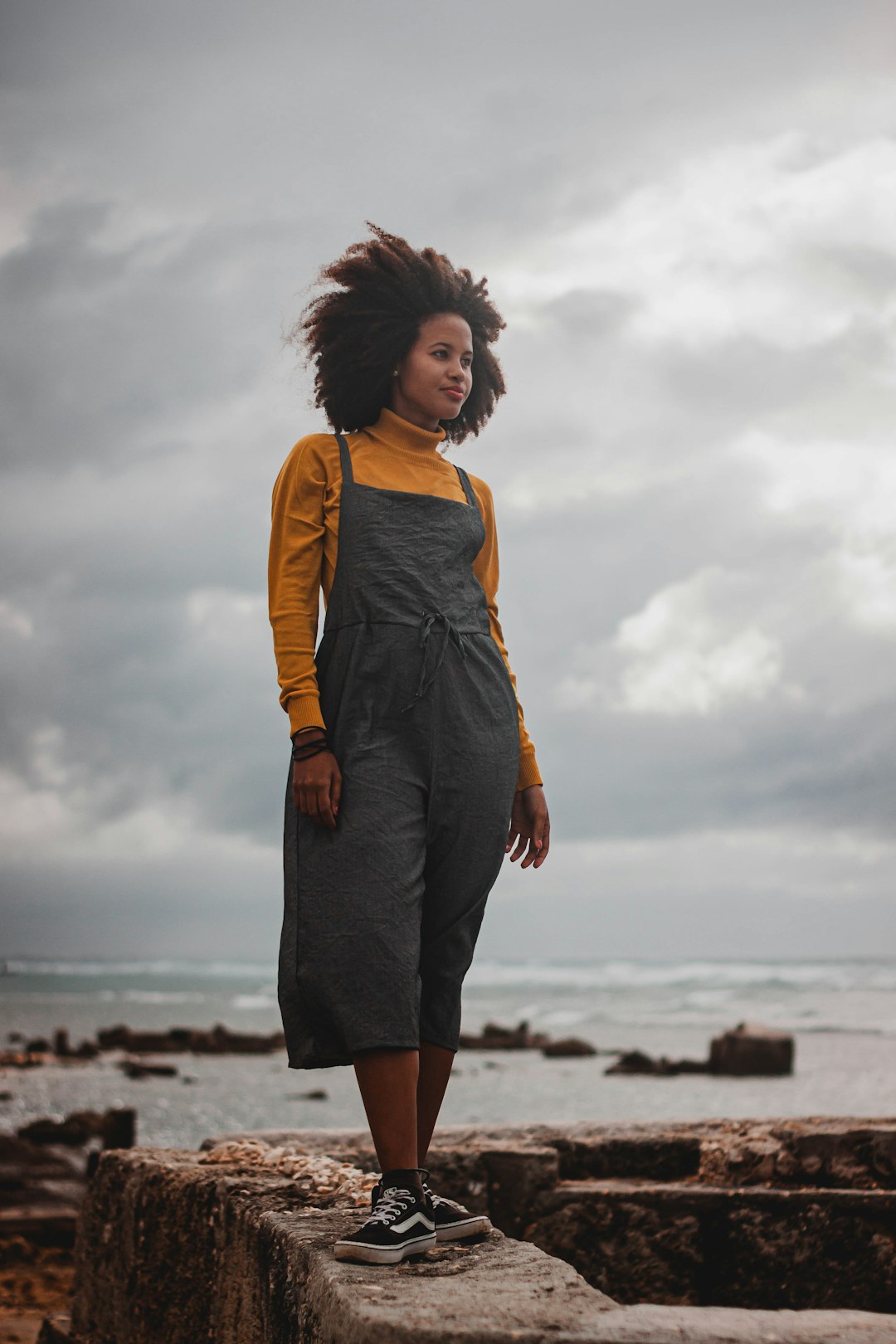 woman in yellow shirt and black skirt standing on beach during daytime