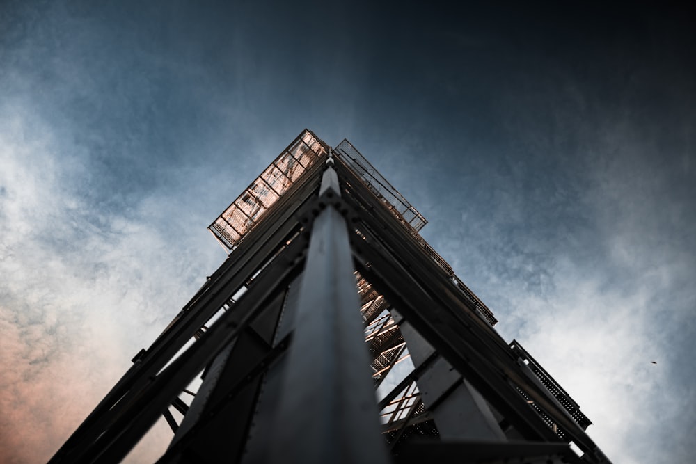 low angle photography of gray metal tower under blue sky during daytime