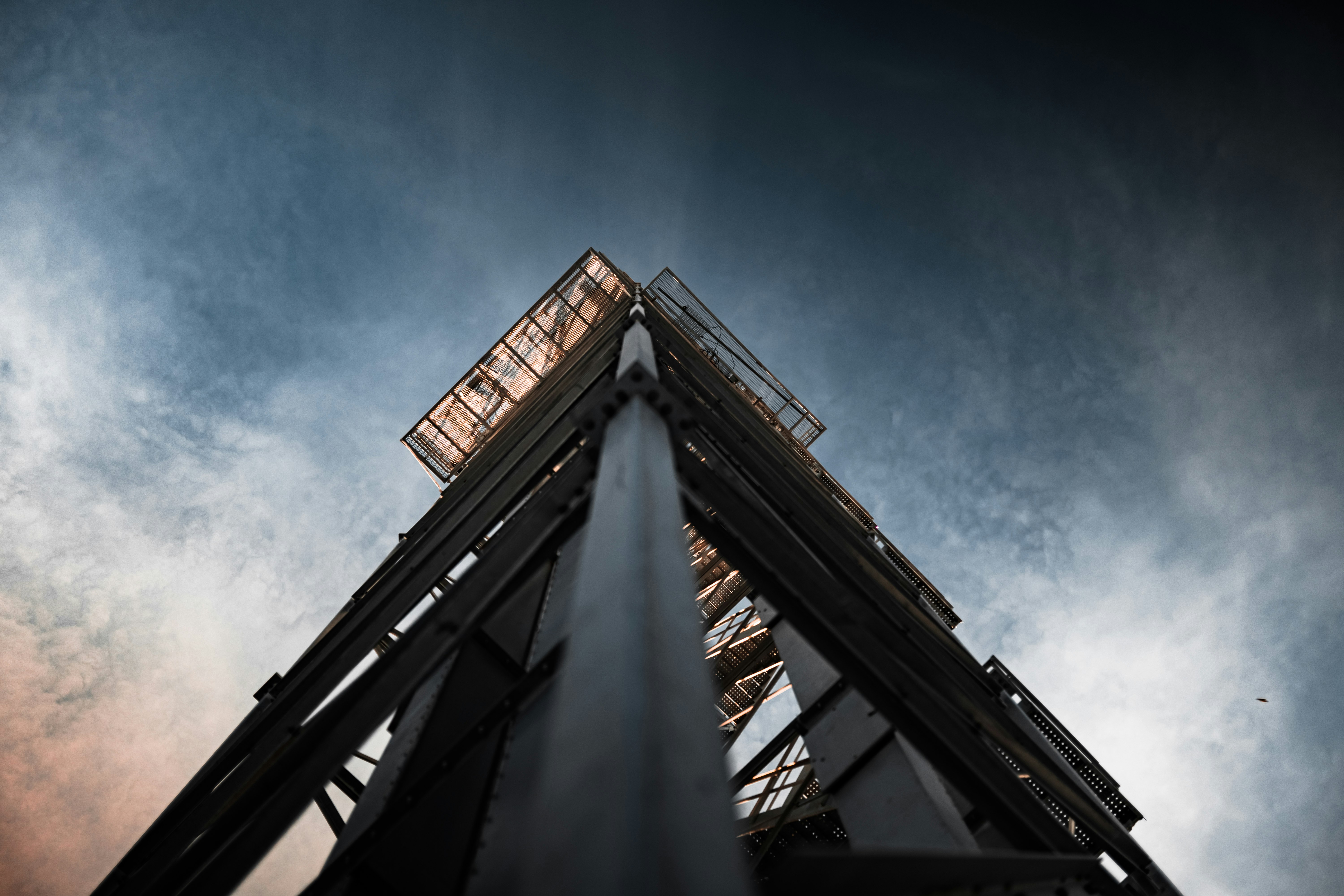 low angle photography of gray metal tower under blue sky during daytime