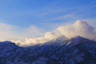 Snow-capped mountain peaks glowing softly under a clear blue sky.