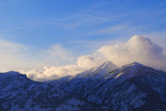 Snow-capped mountain peaks glowing softly under a clear blue sky.