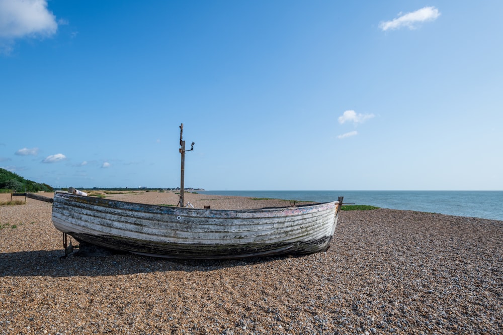 brown wooden boat on brown sand near body of water during daytime