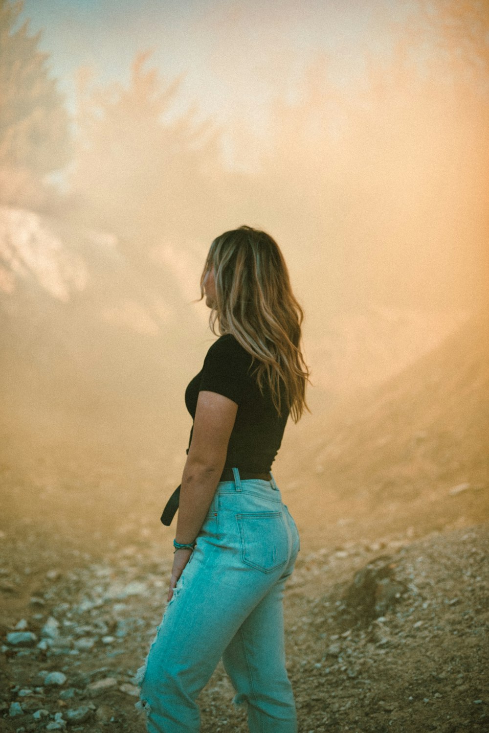 woman in black shirt and blue denim shorts standing on brown field