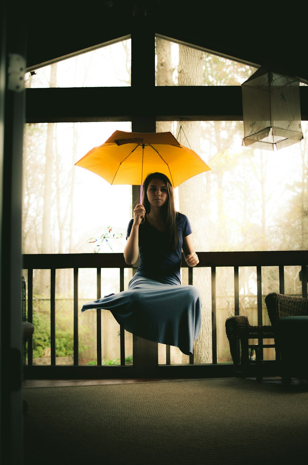 woman in gray dress sitting on brown wooden chair holding umbrella