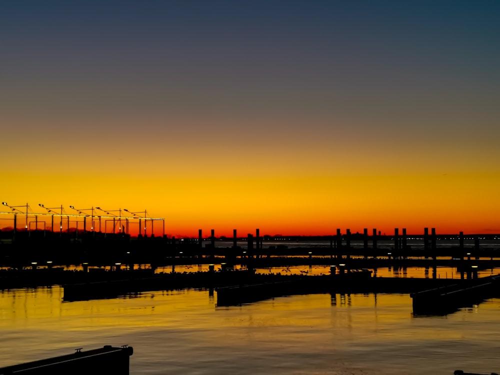 silhouette of people on dock during sunset