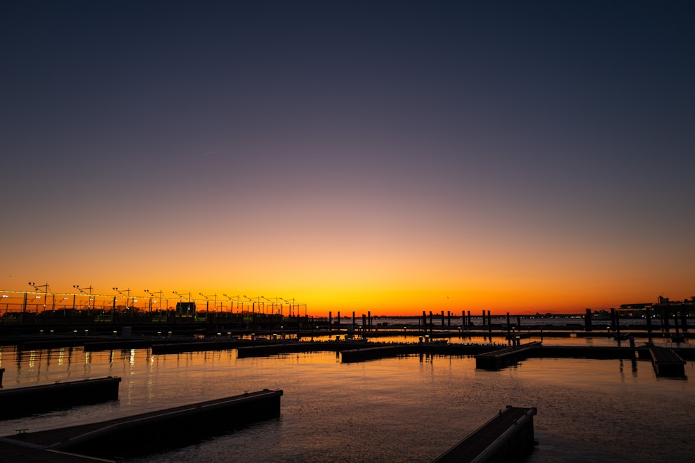 silhouette of dock on water during sunset