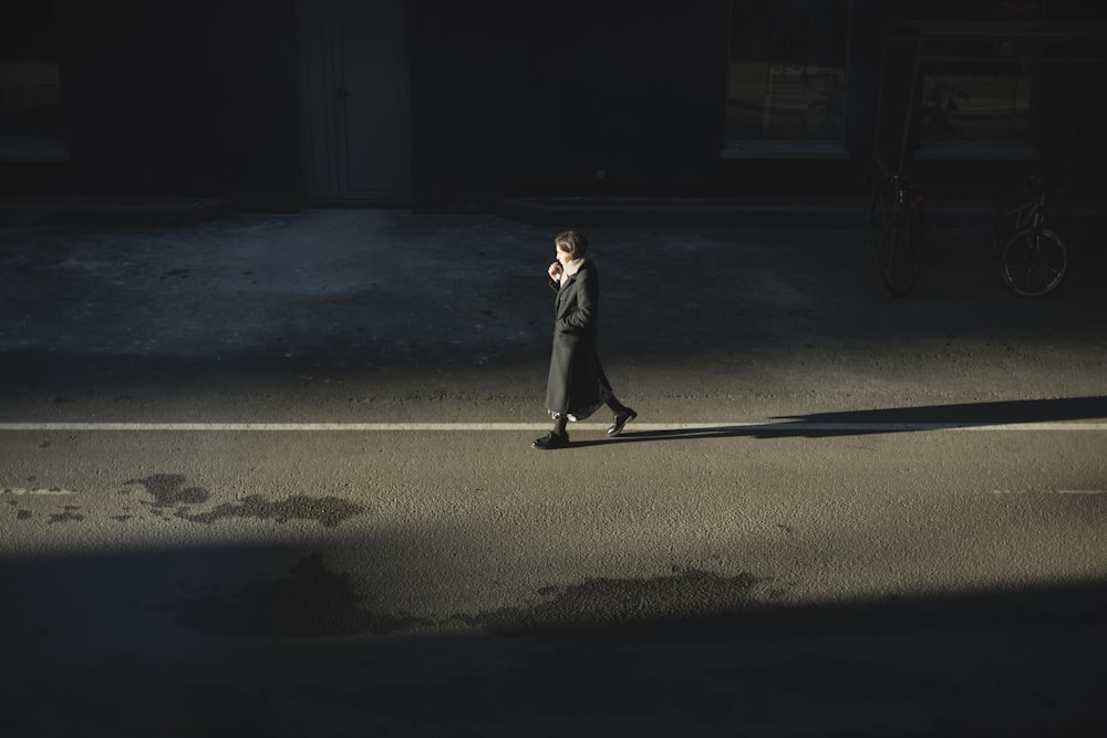 man in white suit standing on gray asphalt road during night time