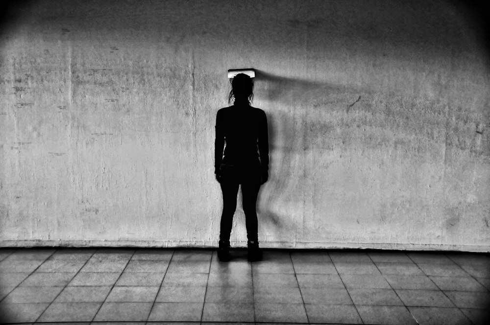 man in black jacket and black pants standing on gray floor tiles