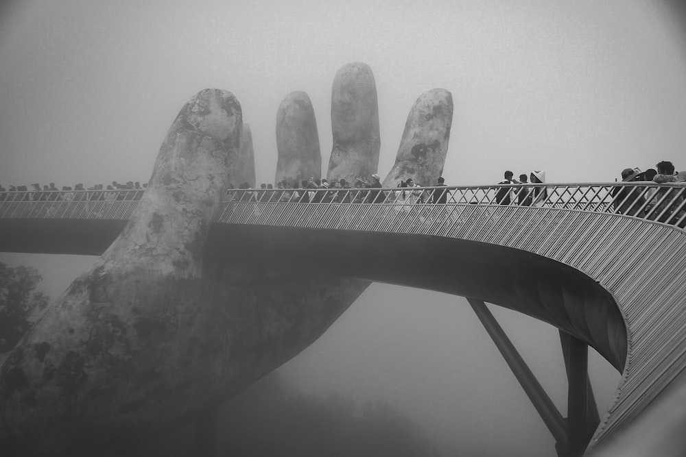 grayscale photo of man standing on bridge