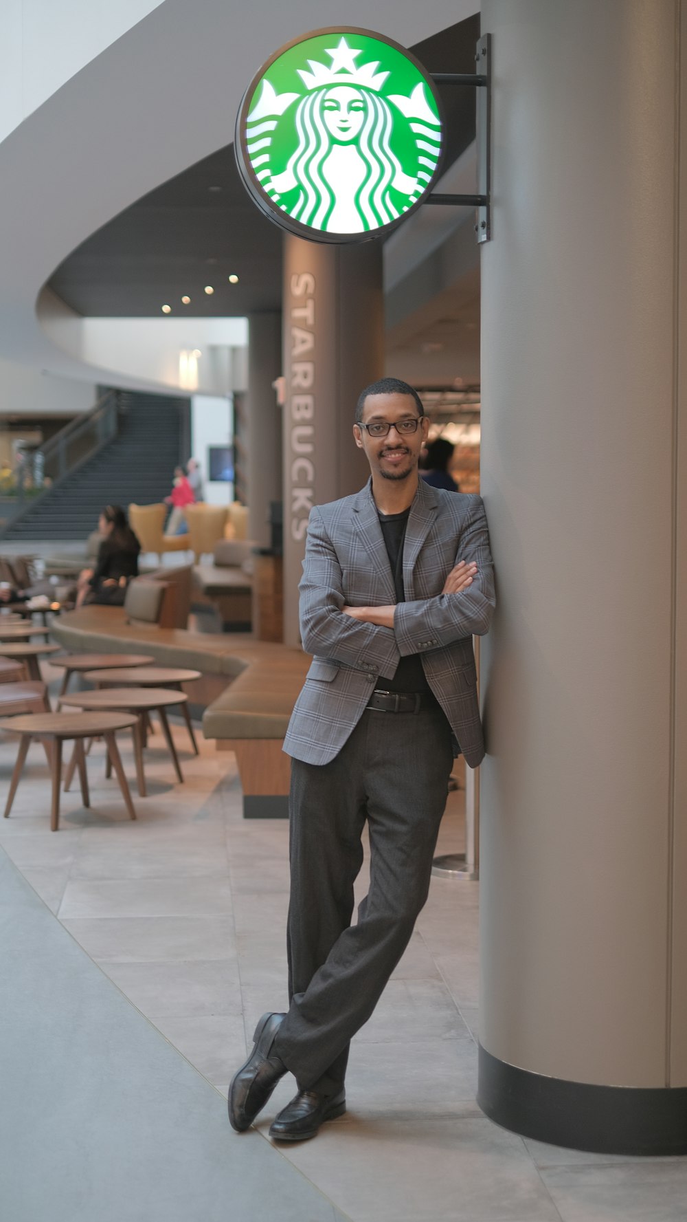 man in black suit standing near brown wooden table