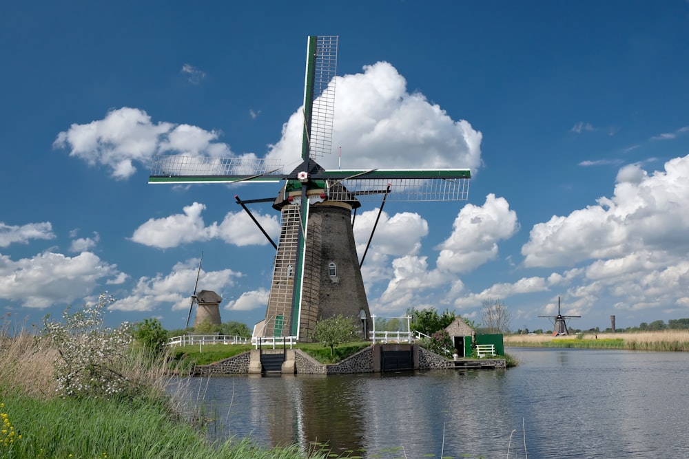 Graue und schwarze Windmühle in der Nähe des Flusses unter blauem Himmel während des Tages