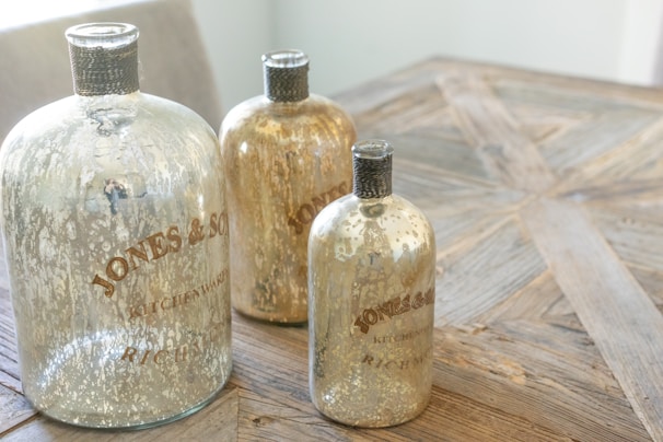 A collection of copper, steel, and fiber water bottles lined up on a rustic wooden table.