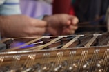 Close-up of hands playing a guzheng with blooming flowers in the background.