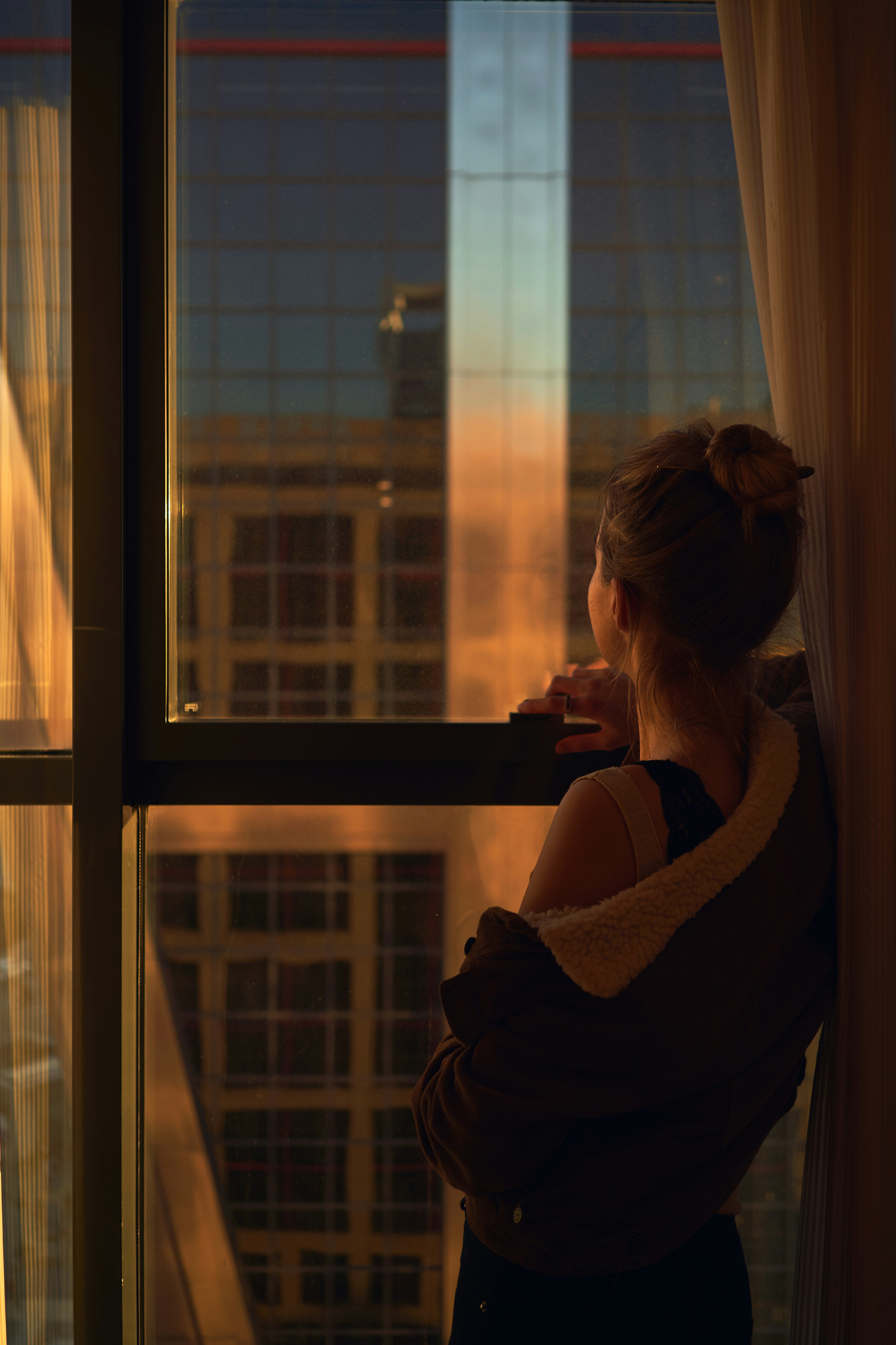A woman looking through the hotel window on the golden hour