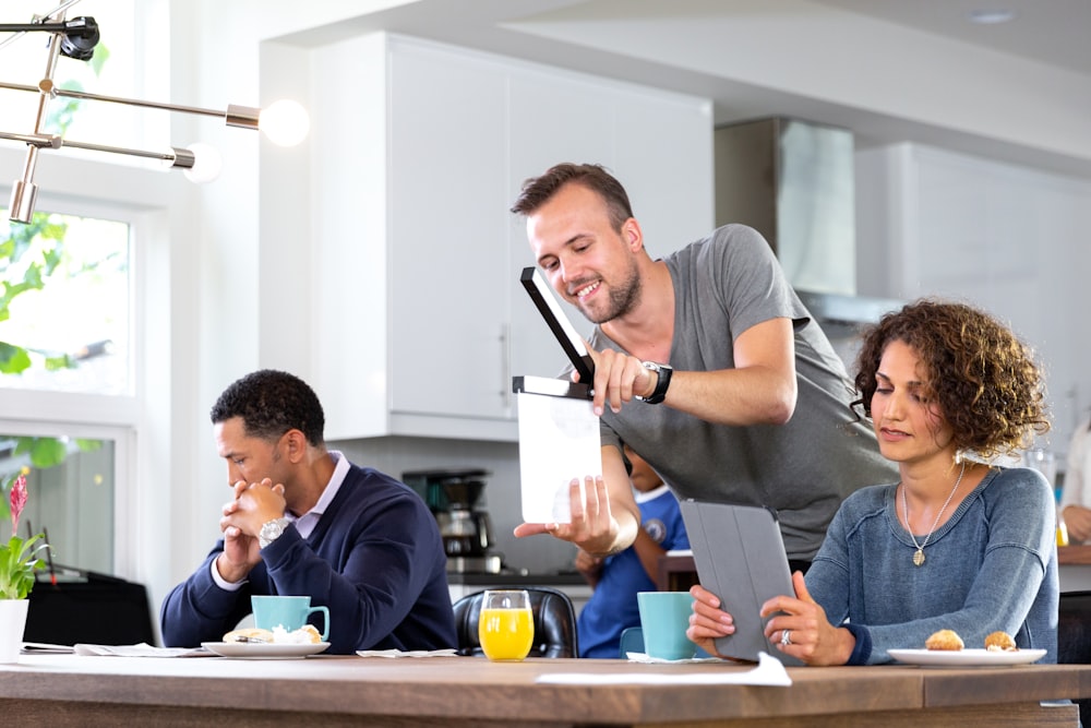 man in gray crew neck t-shirt holding tablet computer