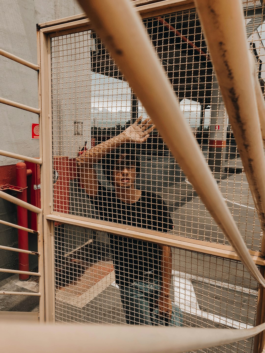 woman in black jacket climbing on white metal fence