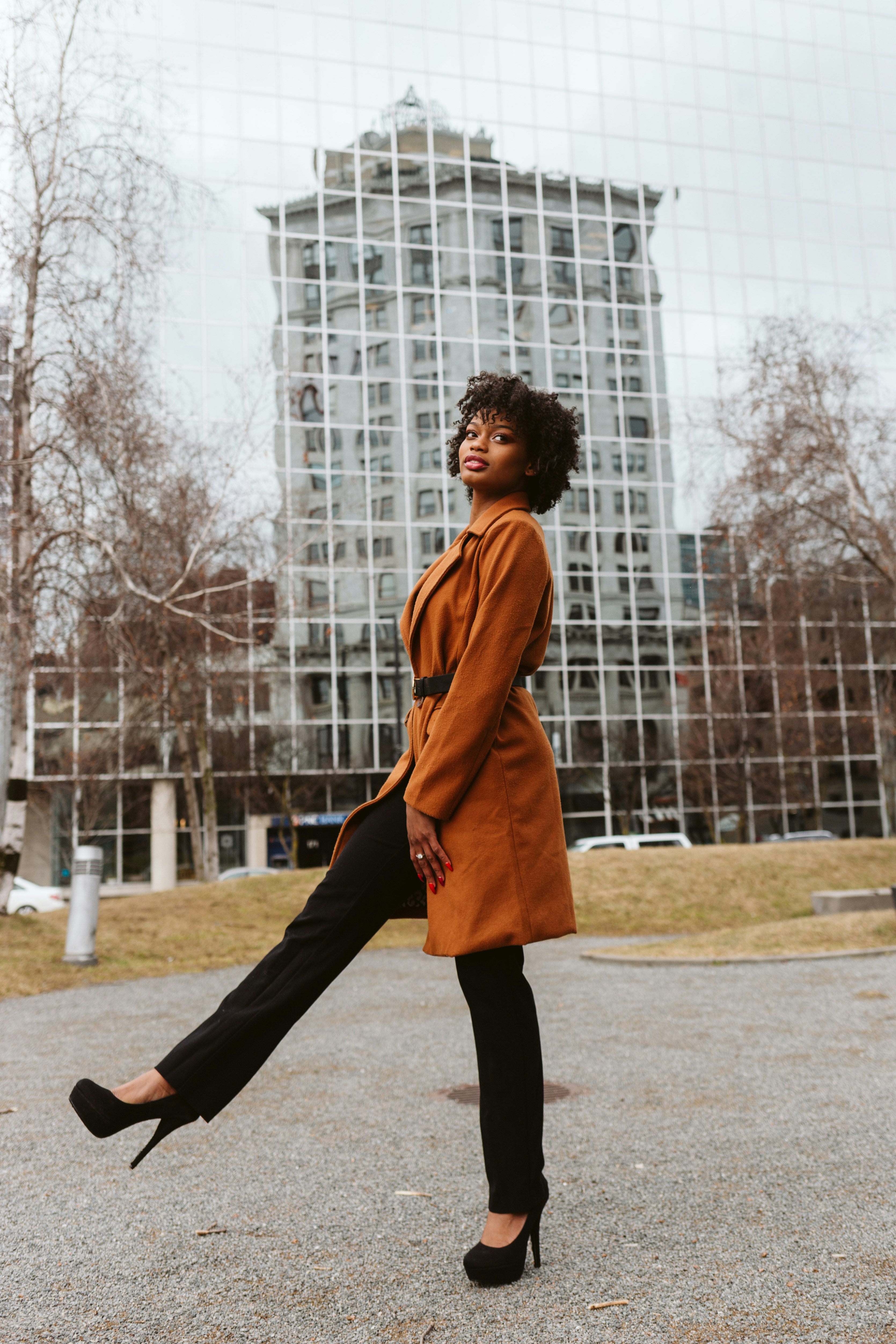 man in brown coat and black pants standing on brown field during daytime