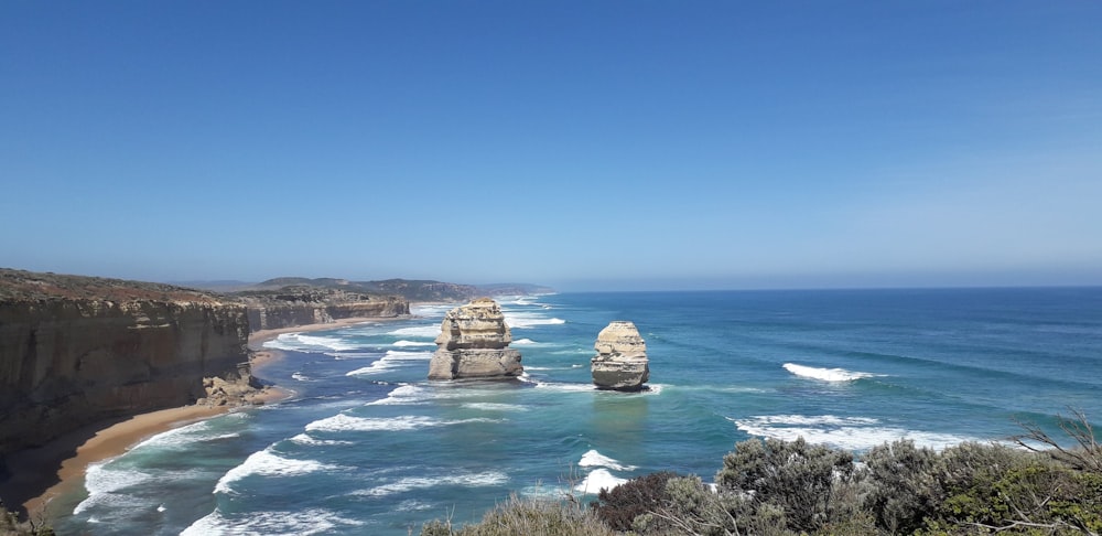 brown rock formation on sea under blue sky during daytime