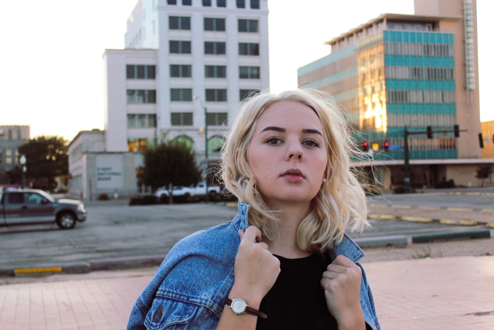 woman in blue denim jacket standing on sidewalk during daytime