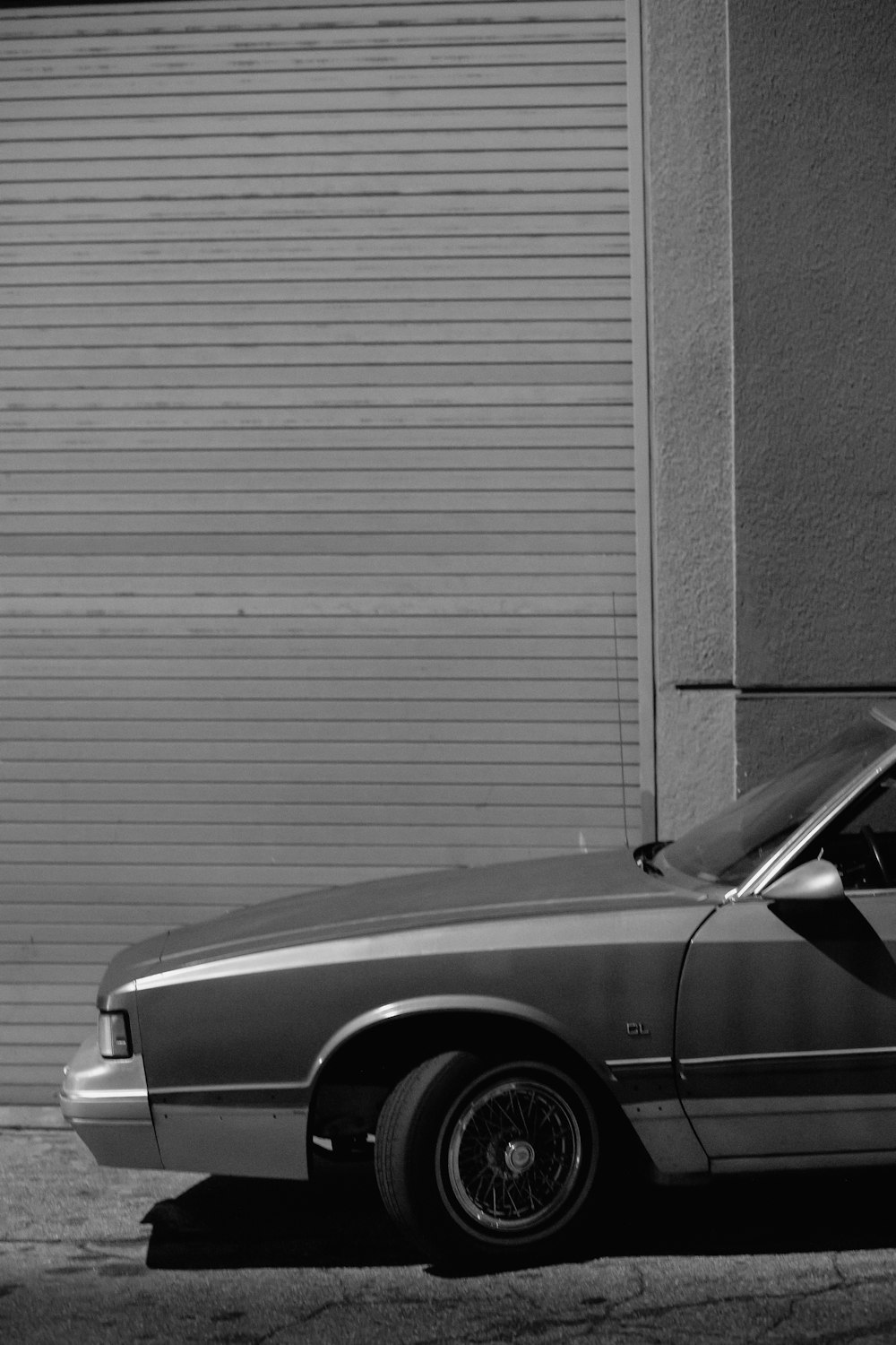 grayscale photo of car near wall