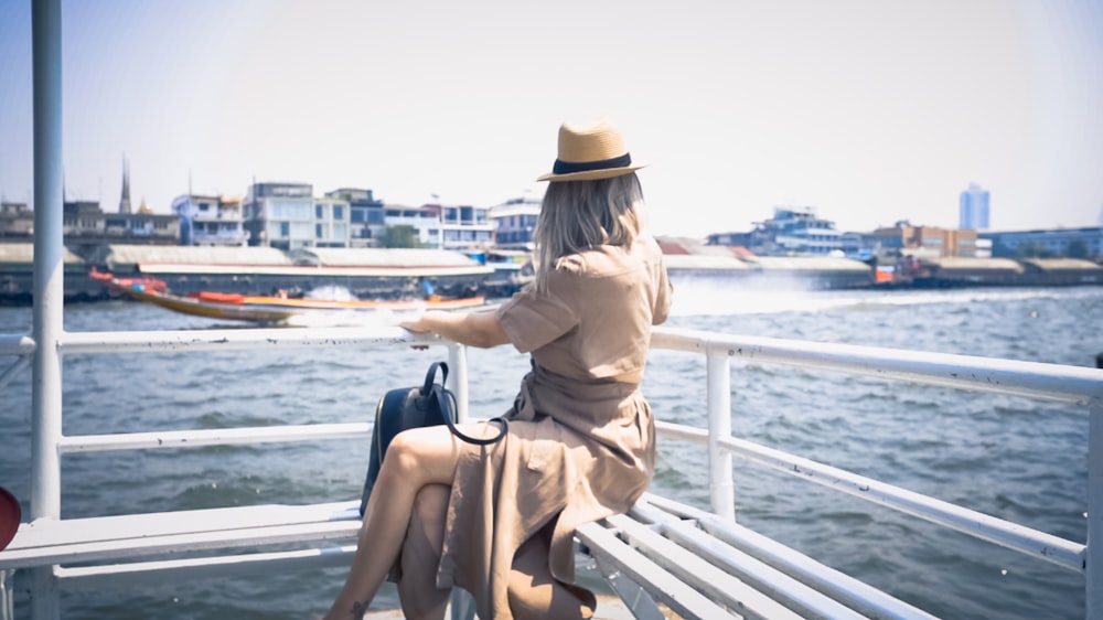 woman in brown dress sitting on brown wooden bench during daytime