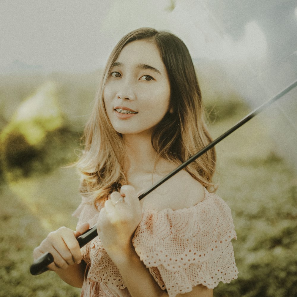 woman in pink floral dress holding black stick