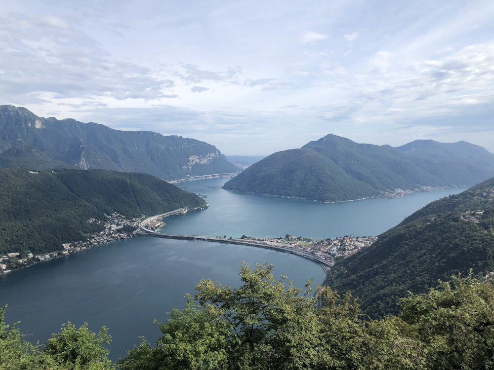 green mountains near body of water under white clouds during daytime