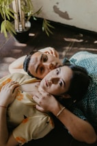 woman in brown button up shirt lying on blue and white floral bed