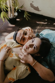 woman in brown button up shirt lying on blue and white floral bed
