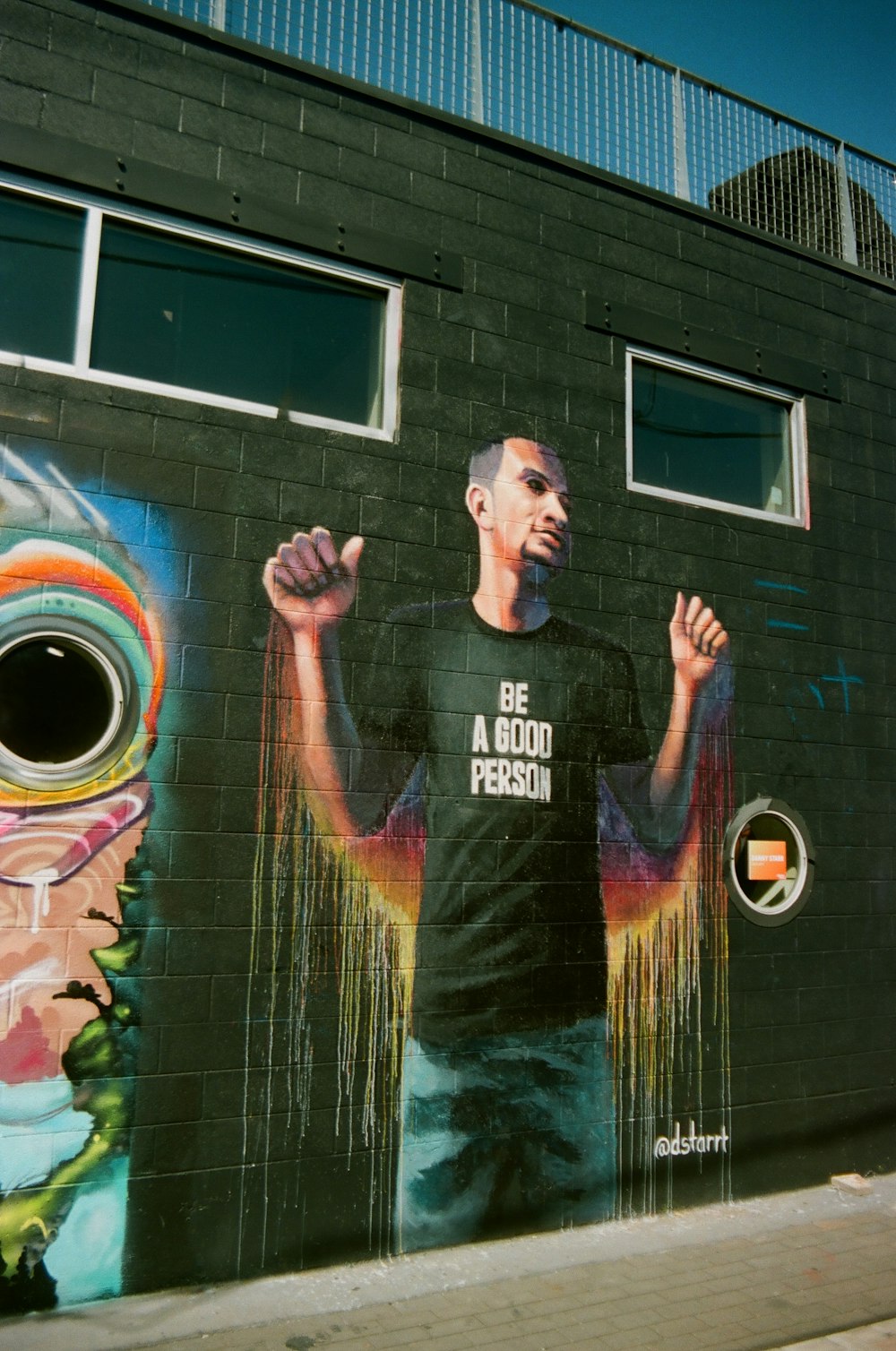 a man standing in front of a wall with a mural on it