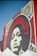 A large mural on a brick wall features a striking black-and-white portrait of a woman surrounded by bold red typography. The words 'Power & Equality' and 'Power to the People' are prominently displayed. Decorative patterns frame the portrait, adding artistic flair to the composition.