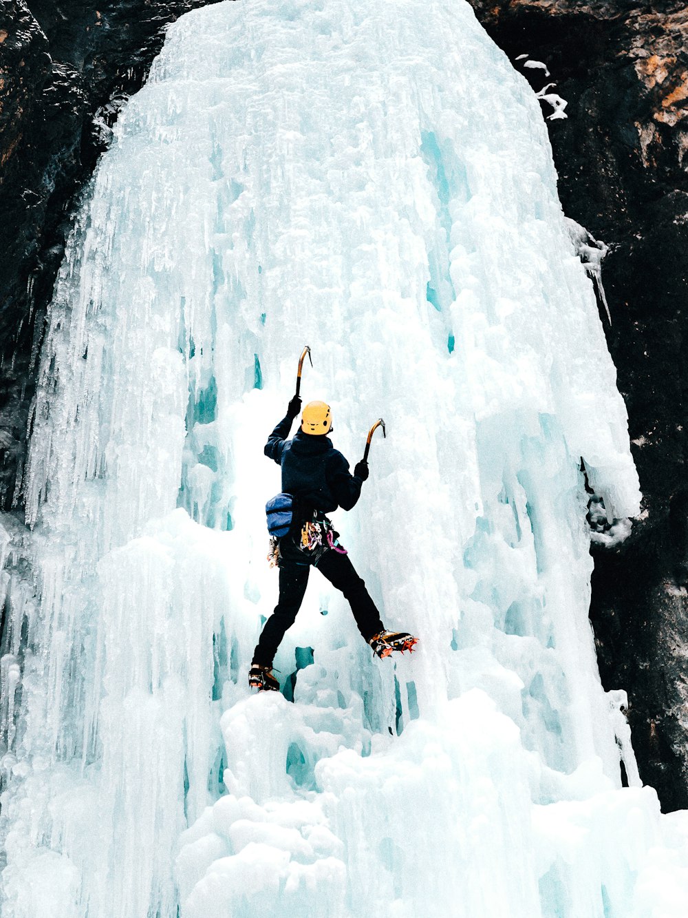 man in black jacket and black pants jumping on ice