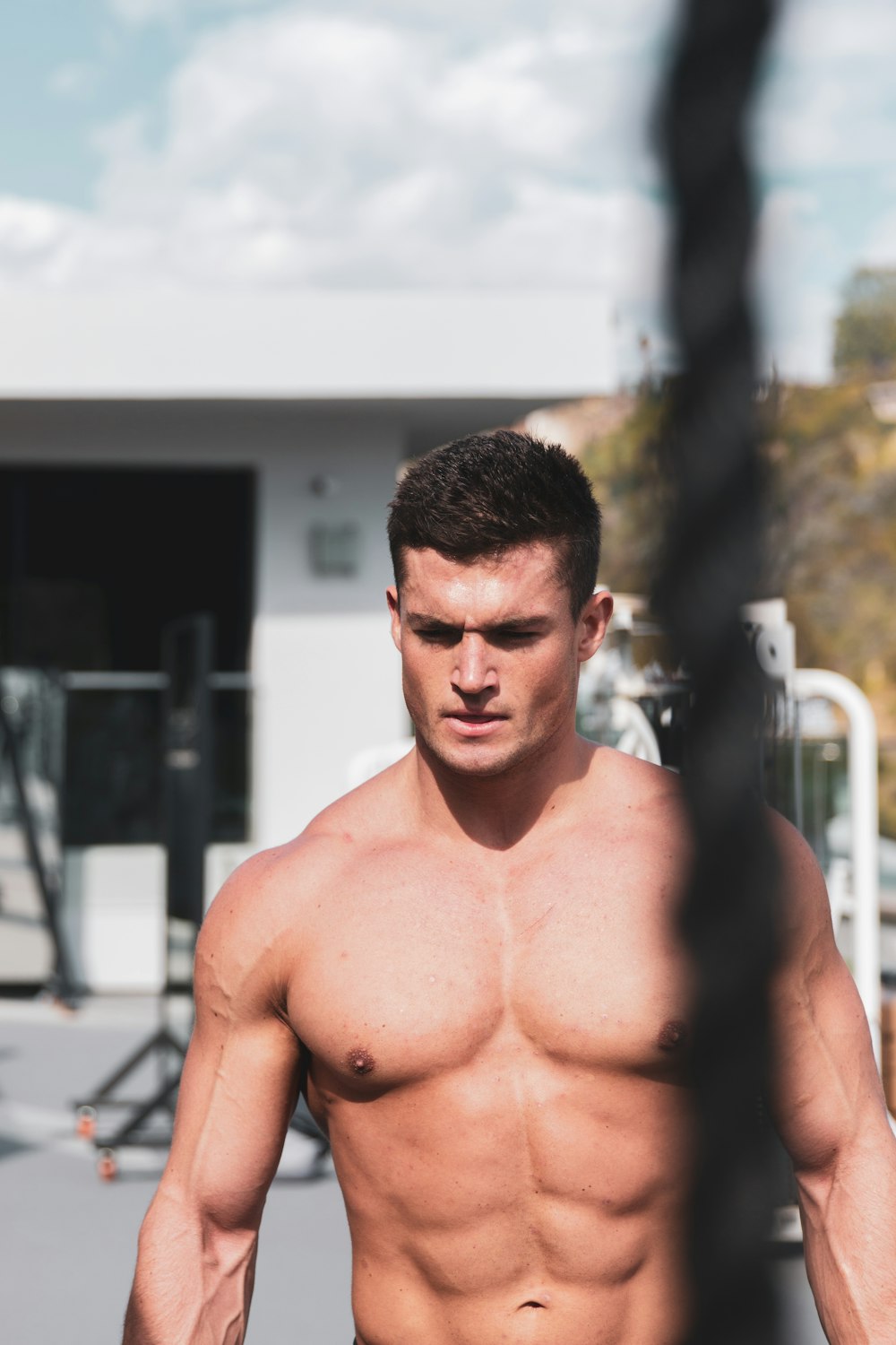 topless man standing near white metal railings during daytime