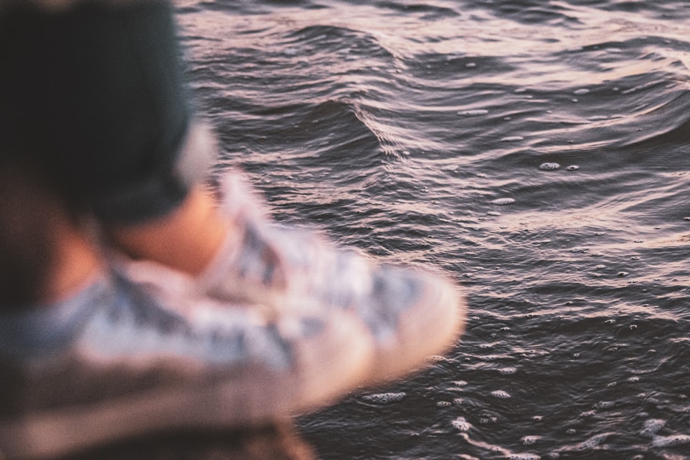 person in black and white jacket on body of water during daytime