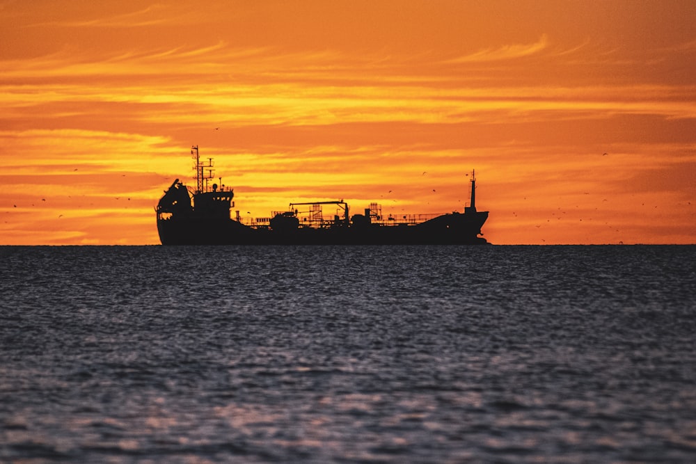 silhouette of ship on sea during sunset