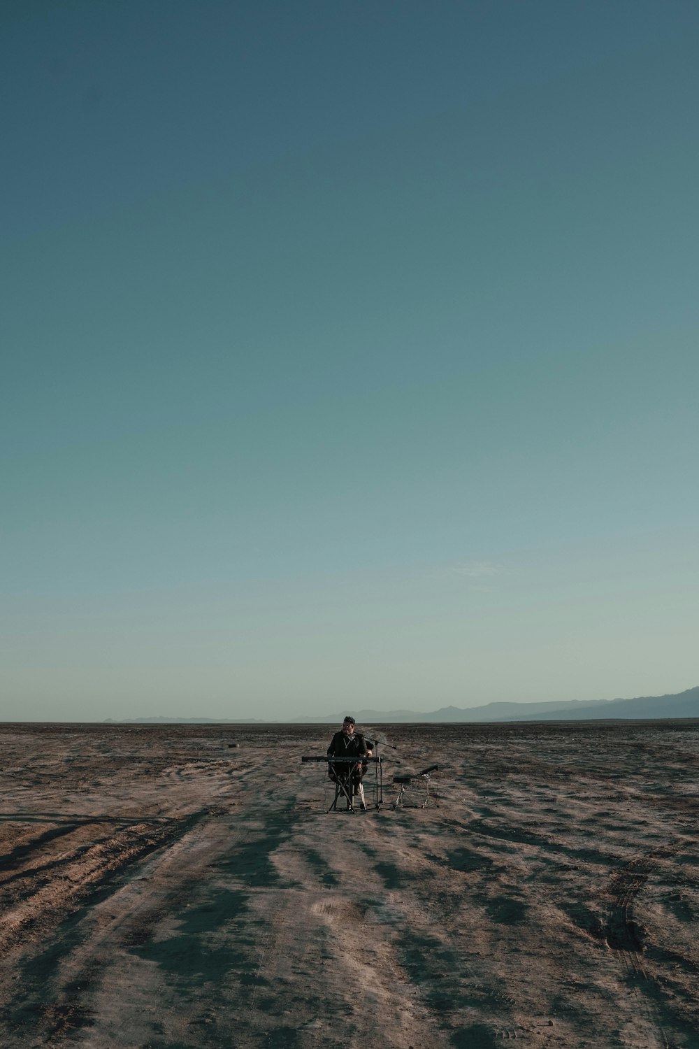 person in black jacket walking on brown sand under blue sky during daytime