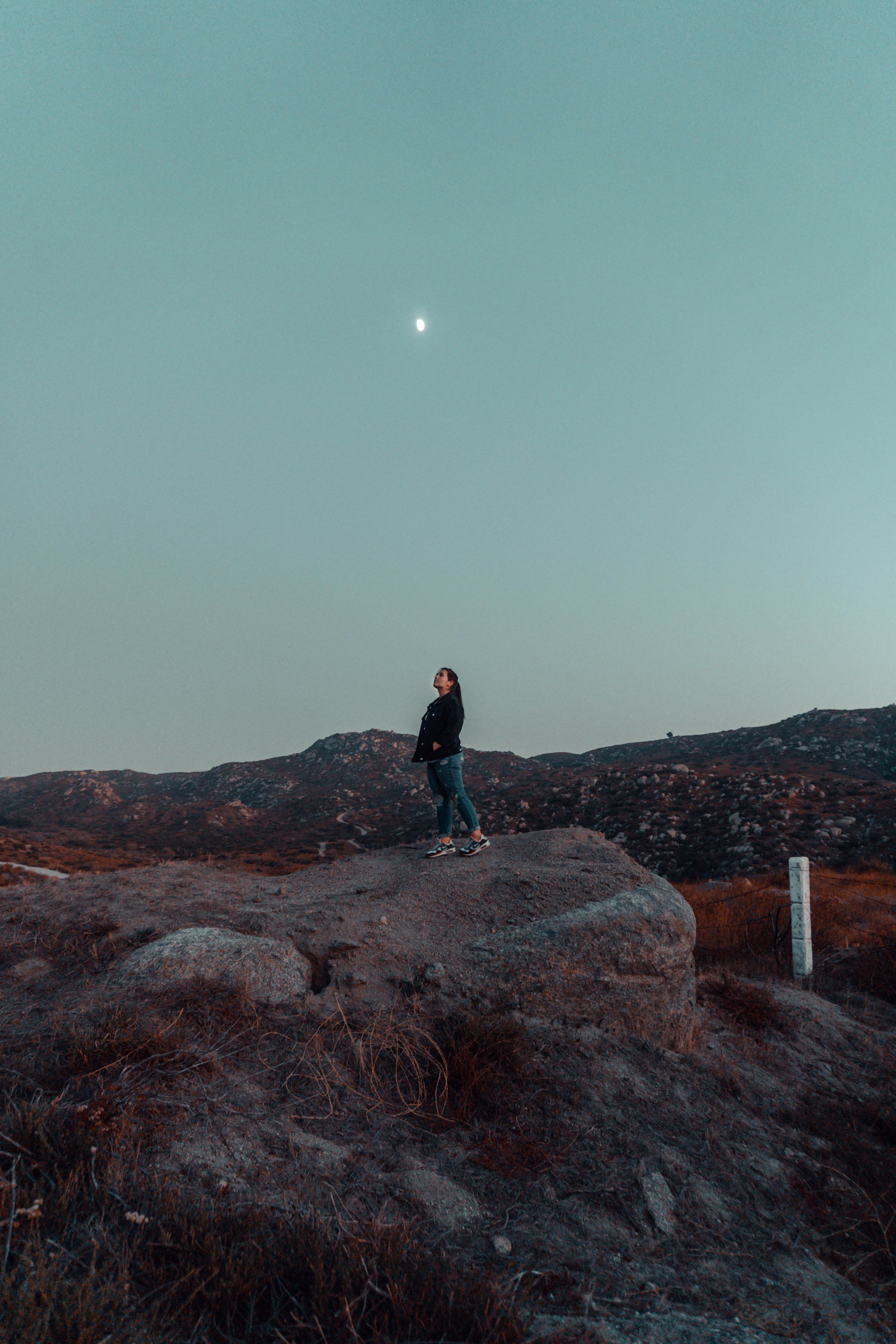 man in black jacket standing on brown rock during daytime