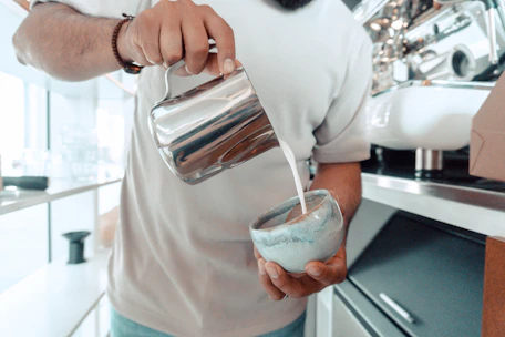 Elegant barista carefully pouring espresso in a sleek, modern coffee shop setting.