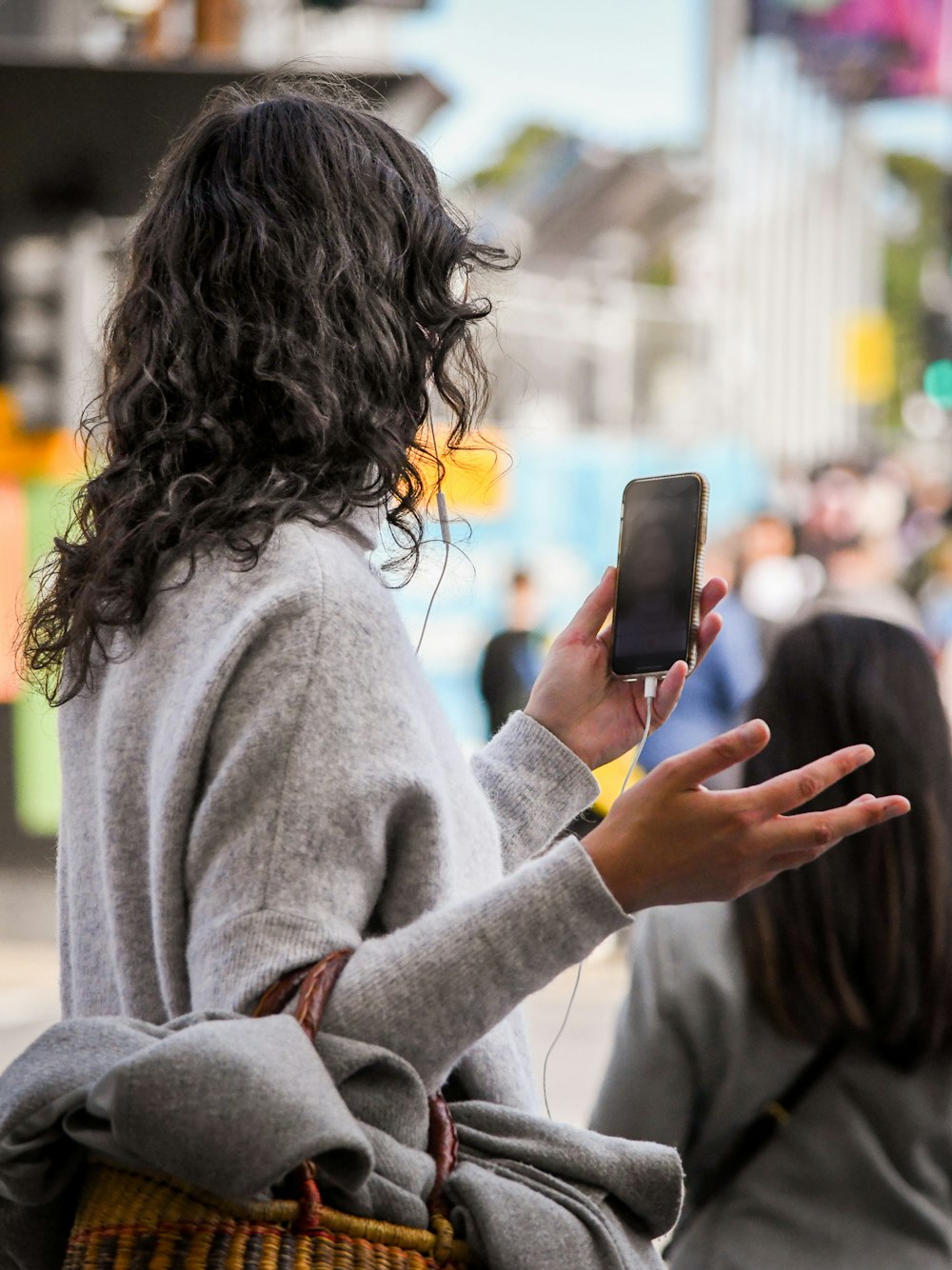 Femme en pull gris tenant un smartphone