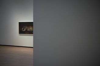 A dimly lit corner of the stable transformed into an art exhibition space with colorful paintings.