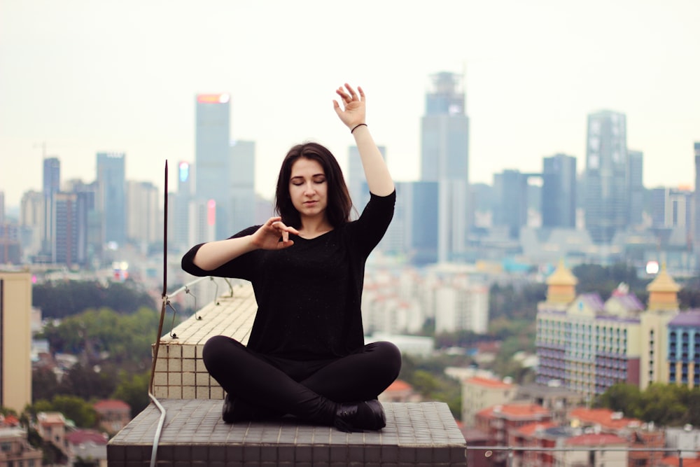 woman in black long sleeve shirt and black pants sitting on white and gray table