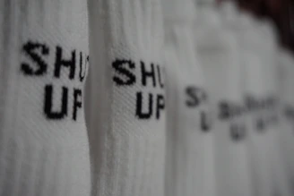 A close-up of a t-shirt with bold, sarcastic office humor typography in muted charcoal on a washed black background.