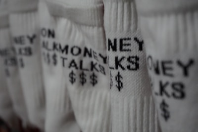 Several pairs of white socks feature the phrase 'MONEY TALKS' along with dollar signs in black text. The focus is on the texture of the fabric and the bold lettering.