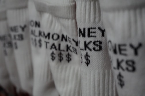 Several pairs of white socks feature the phrase 'MONEY TALKS' along with dollar signs in black text. The focus is on the texture of the fabric and the bold lettering.